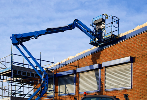 Operator controlling MEWP boom lift during NPORS N108 training at construction site