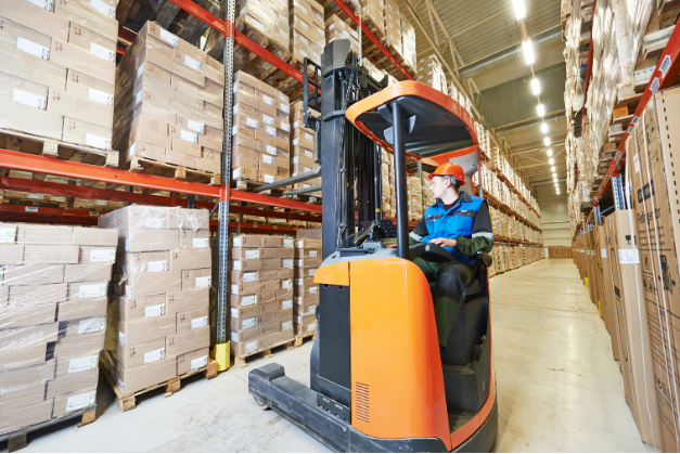 Operator manoeuvring a reach truck in narrow warehouse aisle during NPORS N003 training
