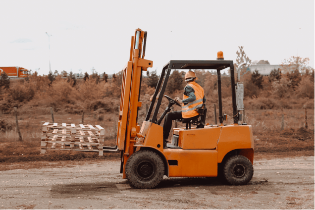 Trainee operating rough terrain lift truck on uneven construction site during NPORS N009 training